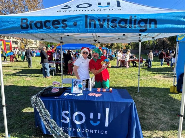 SOUL Orthodontics holiday booth with staff in Santa hat and elf costume promoting braces and Invisalign.