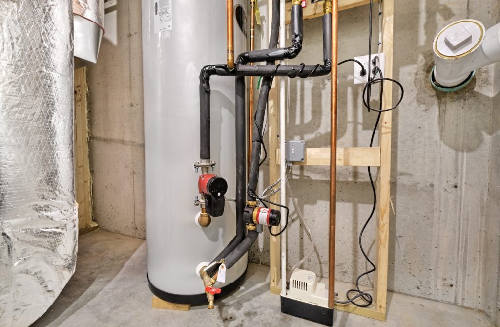 Hot water heater with insulated copper piping, circulator pumps and condensate pump in unfinished basement